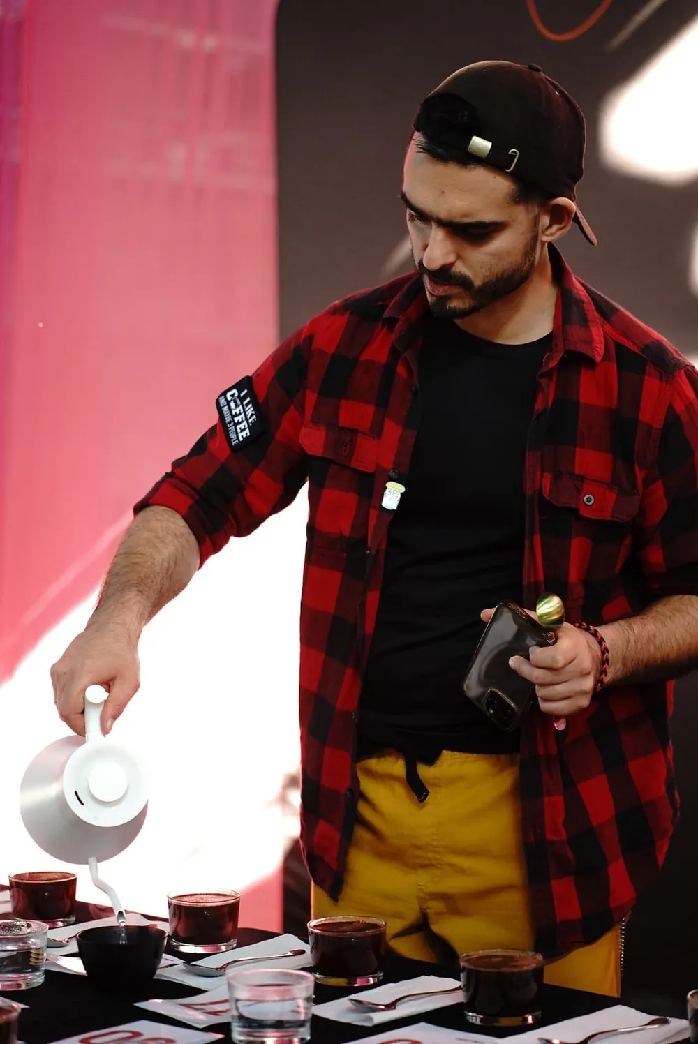Kamil in his black and red plaid shirt, cupping coffee